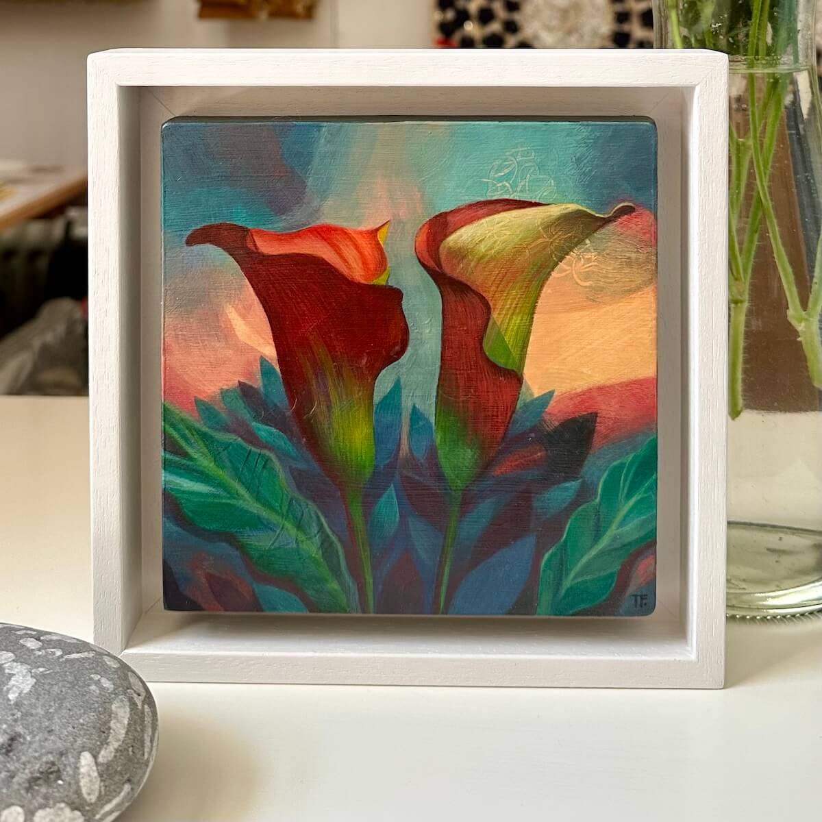 Teresa Flavin's Peach Callas painting in a white frame on a white table.