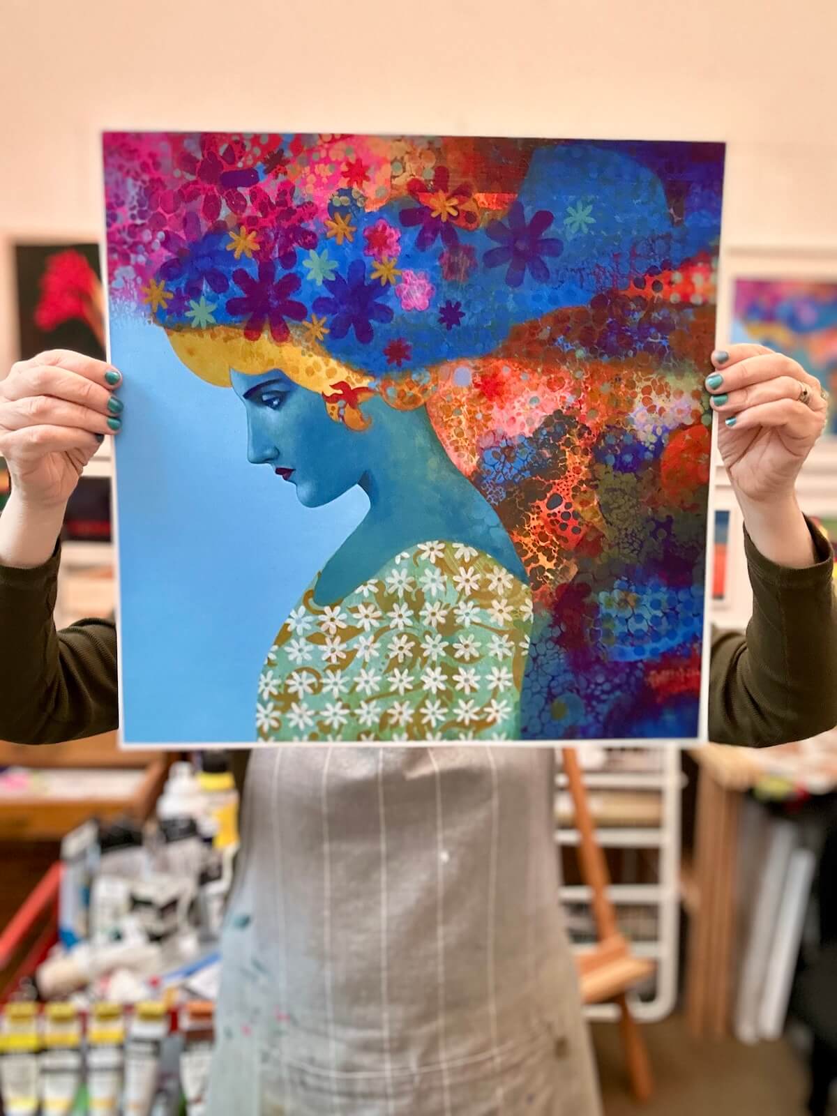 Person holding a colorful artwork of a stylized woman with flowers.