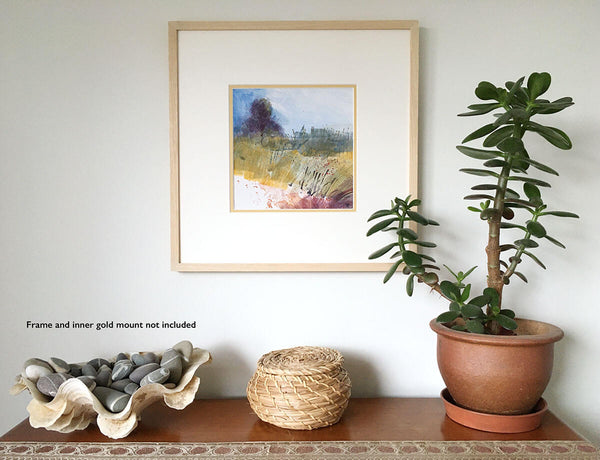 High Summer, square acrylic gouache landscape painting by Teresa Flavin, blue sky, violet tree, golden green land and maroon ground, shown in white mount and wood frame on wall.