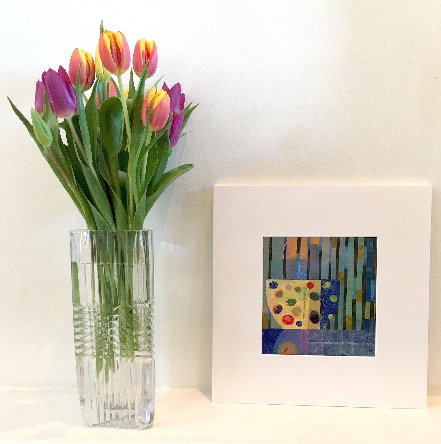 Jellybabies by Teresa Flavin Artist, abstract still life mixed media painting shown in white mount on shelf next to tulips in vase.