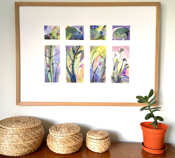 Drench, abstract botanical art print by artist Teresa Flavin, flower forms, leaves, lily pad and stems in gold, green, violet, magenta, blue and black, shown in wood frame on wall.